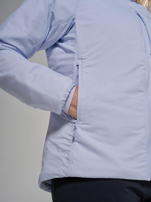 A close-up of a person wearing a light periwinkle blue puffer jacket, showing the side pocket with a hand inside and the smooth quilted fabric.